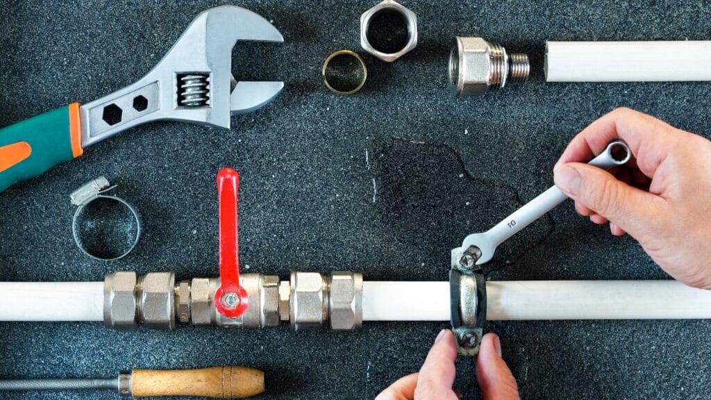 Plumber repairing a pipe valve with an adjustable wrench in Cocoa