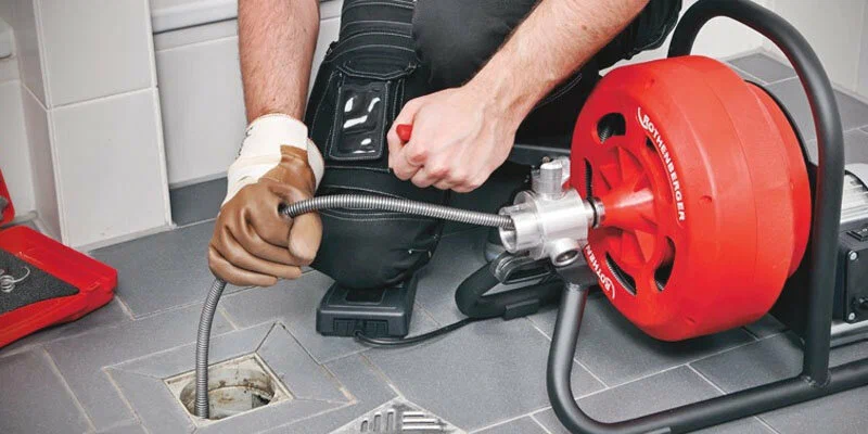 Plumber using a drain-cleaning machine in Cocoa