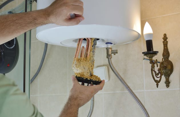 Technician removing mineral buildup from a water heater in Cocoa