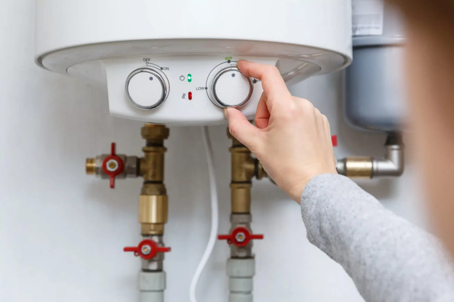Homeowner adjusting the temperature controls on a water heater in Cocoa